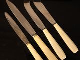 three knives are sitting on a black surface with a knife in the middle of them