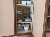 a cabinet with dishes and cups in it in the kitchen