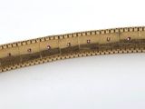 a close up of a gold colored metal ruler on a white surface