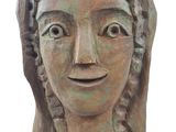 sculpture représentant la tête d'une femme souriante, posée sur un socle en bois
