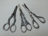 four pairs of scissors are lined up on a white surface