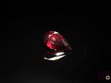 un gros plan d'un diamant rouge posé sur une surface noire