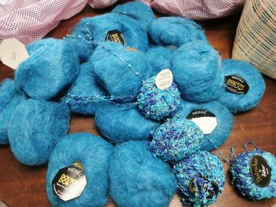de nombreuses pelotes de laine bleue posées sur une table en bois