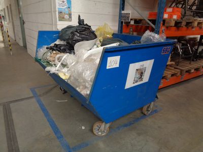a blue cart filled with garbage in a warehouse