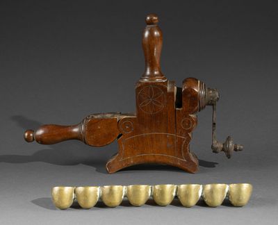 an antique wooden grinder with eight brass cups and a wooden handle