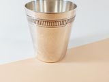 a silver cup sitting on top of a table next to a white wall