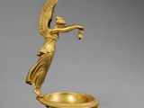 une figurine en or représentant un ange tenant un bol, posée sur un socle
