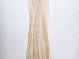a white dress hanging on a hanger against a white wall