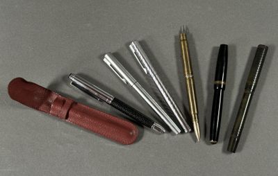 cinq stylos et un étui en cuir sur la table