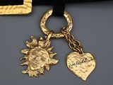 gold charm with a sun and a heart on a black velvet belt