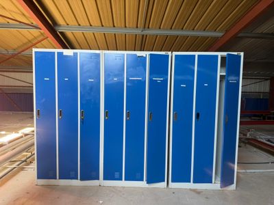 several blue metal lockers in a warehouse with a wooden ceiling