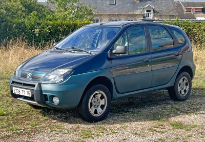 a small blue car parked on the side of the road