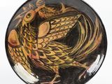 a black and yellow plate with a bird painted on it