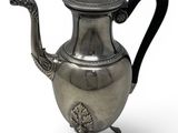 an antique silver teapot with a black handle on a white background