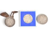 deux pièces d'argent et une petite pièce d'argent posées sur une surface blanche