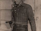 black and white photo of a man in a cowboy outfit holding a gun