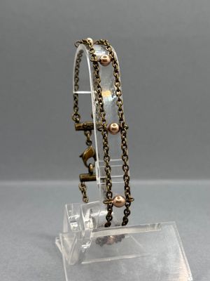bracelet en cristal avec des perles dorées, présenté sur un socle en acrylique transparent