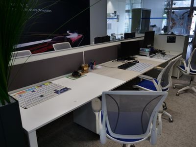 une photo d'un bureau cloisonné avec deux ordinateurs et une plante