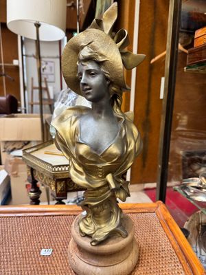 bronze statue of a woman with a hat on top of a table