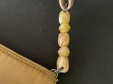 beige leather purse with a beaded strap on a black surface