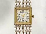 une montre en or avec un cadran blanc orné de perles