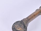 a metal object with a handle on a white surface