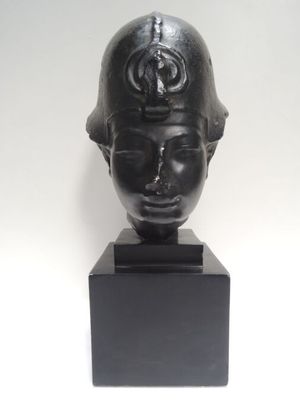 une sculpture noire représentant la tête d'une femme coiffée d'un casque