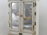 a small white cabinet with a mirror on top of it