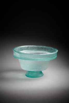 une image représentant un bol en verre posé sur un socle, sur fond noir