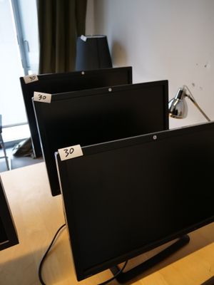 trois écrans d'ordinateur posés sur un bureau dans une pièce
