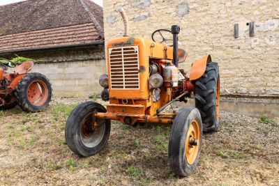deux vieux tracteurs garés devant un bâtiment en briques