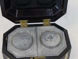 an image of a black and gold box with two silver plates in it