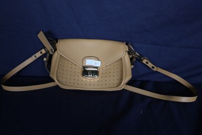 sac à main en cuir beige orné de boucles métalliques sur fond bleu