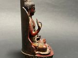 statue of a person sitting on a rock with a bird in his hand