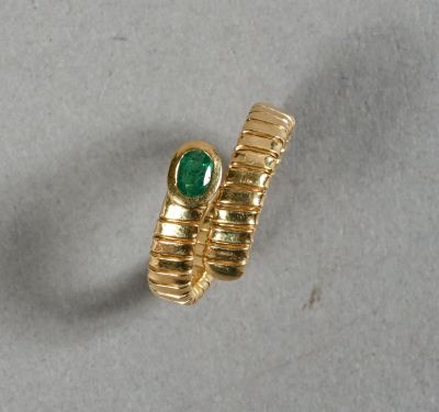 gros plan d'une bague en or avec une pierre verte
