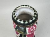 a small vase with a black and white design on it