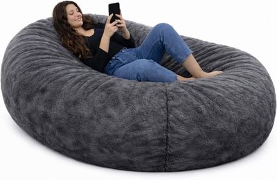 La femme est assise sur le pouf et utilise son téléphone portable.