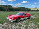 une voiture de sport rouge et blanche garée dans un pré