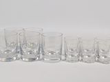 six shot glasses lined up in a row on a white surface