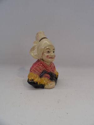 une petite figurine représentant une femme assise sur une surface blanche