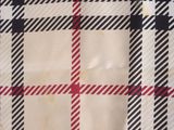 a close up of a black and white plaid fabric with a red stripe