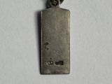 a close up of a small metal tag on a white surface