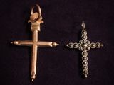 deux pendentifs en forme de croix, en argent et en or, sur fond noir