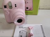 a pink camera sitting next to a green box on a table