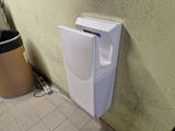 un distributeur de papier toilette fixé au mur, à côté d'une poubelle