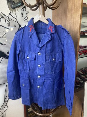 une veste bleue posée sur un portant devant un mur orné d'un dessin