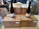 deux bouteilles de vin posées sur des cartons, eux-mêmes posés sur une table
