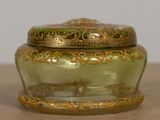 a green glass jar with a gold decoration on it