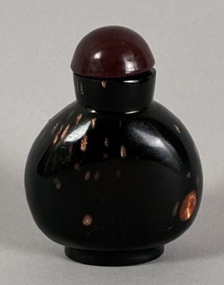 a small black vase with a red lid sitting on a table