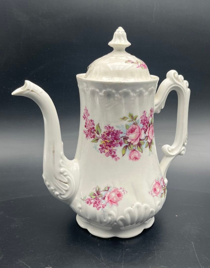 LIMOGES Une cafetière en porcelaine à fond blanc et décor peint polychrome floral. Signée au revers. H 24 cm. (fêles,...